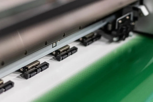 Close-up of a modern printing press applying green ink, representing sustainable and eco-friendly printing practices.