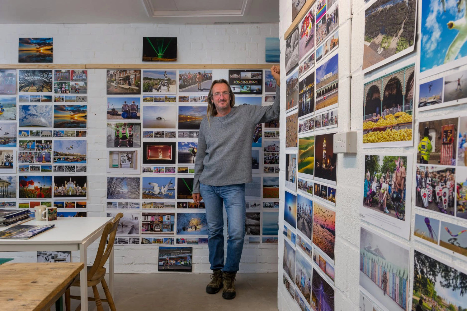 Nigel Swallow, founder of the Brighton & Hove Calendar, in his studio surrounded by colourful Brighton photography featured in past calendar editions.