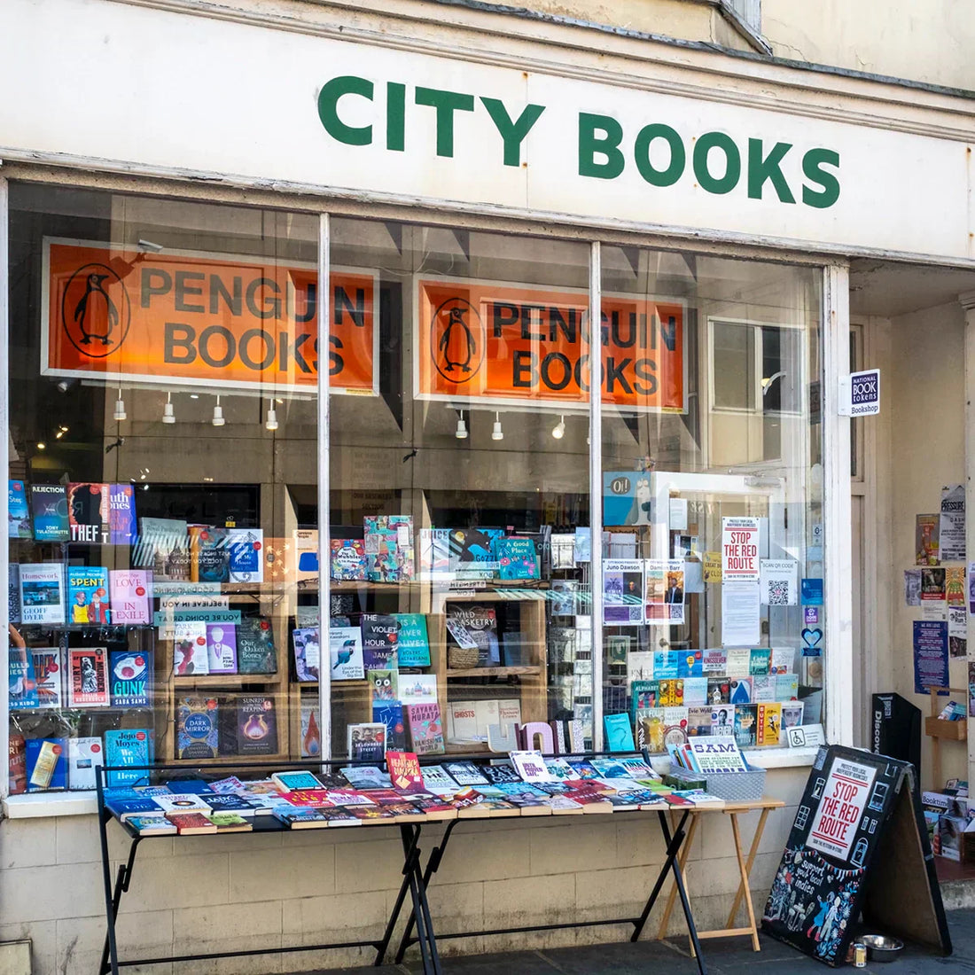 Exterior of City Books in Hove, an independent bookshop on Western Road with a book laden table outside and window displays filled with books.